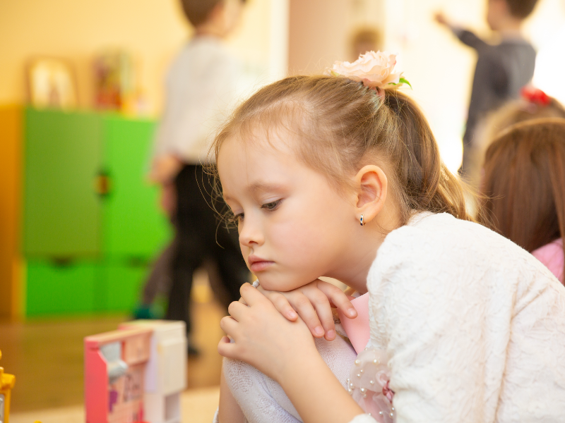 Petite fille assise regardant le sol